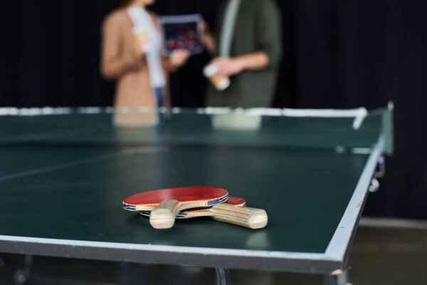 Two employees share laughter and ideas while enjoying a game of ping pong in the office setting.