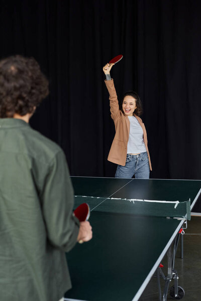 Two colleagues play ping pong in the office, highlighting teamwork and friendly rivalry.