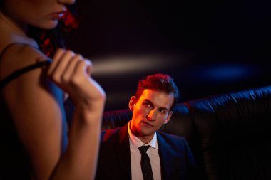 Bir çift derin bir bağ kuruyor, gölgeler ve cazibeyle çevrili bir salonda..