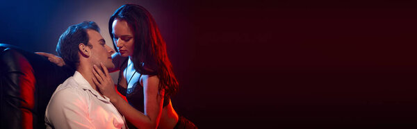 Любящая пара разделяет момент страсти, глядя друг другу в глаза в тускло освещенном пространстве.