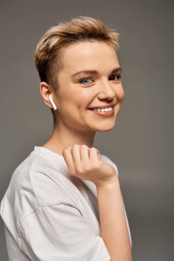 Genç bir kadın minimalist bir stüdyoda gülümseyişiyle pozitiflik ve güven yayar..