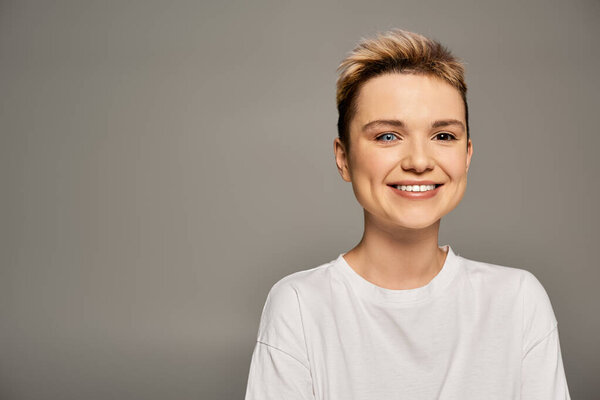 A young woman exudes confidence and joy, embracing her body in a simple, elegant atmosphere.