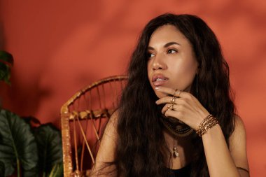 Dalgalı saçları olan genç bir kadın, yaz mevsimini ılık renklere karşı yansıtan zarifçe poz verir..