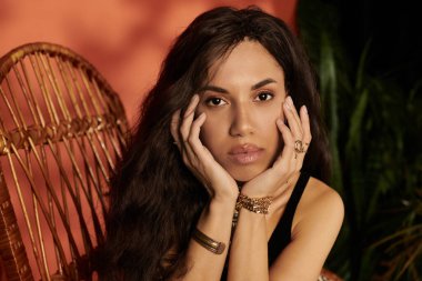 Güzel genç bir kadın zarif bir şekilde poz verir yemyeşil ve sıcacık renklerle, kendinden emin bir şekilde..