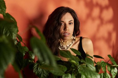 Genç bir kadın zarif bir şekilde canlı bitkiler arasında poz veriyor, eşsiz yaz tarzını sergiliyor..