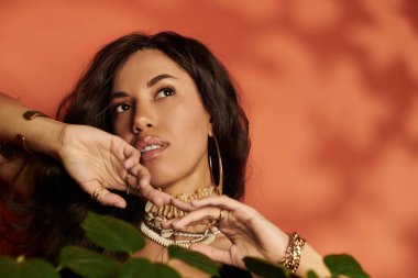 Güzel bir kadın zarif bir şekilde yemyeşil ortamda poz veriyor, yaz atmosferini ve moda modasını somutlaştırıyor..