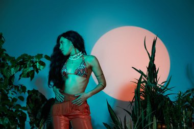 Genç bir kadın kendine güvenini ve tarzını sergiliyor. Yeşillik içinde yaz modasını sergiliyor..