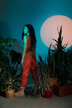 Genç bir kadın canlı bitkiler arasında zarifçe poz veriyor, yaz enerjisi yayıyor..