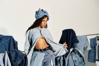 Genç bir kadın yaz aylarında parlak bir moda stüdyosunda şık kot giysileri sergiliyor.