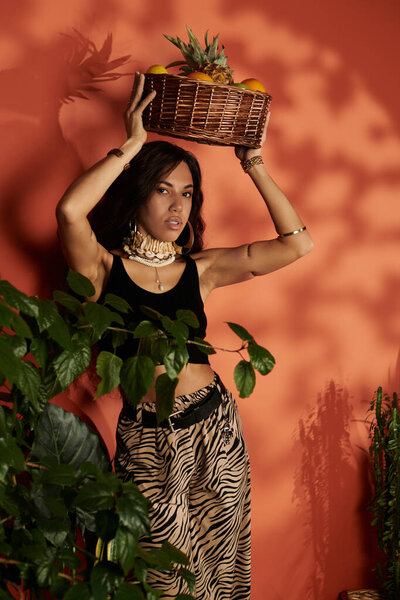 Молодая женщина демонстрирует летний стиль, балансируя корзину фруктов, излучая радость.