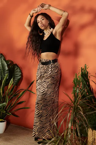 Güzel genç bir kadın cesur bir turuncu arka plana karşı özgüvenle poz veriyor, yaz zarafeti saçıyor..