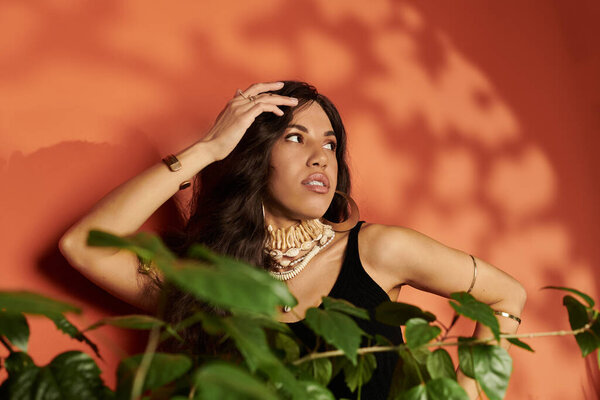 A young woman with vibrant style poses elegantly against a warm colored wall, radiating confidence.