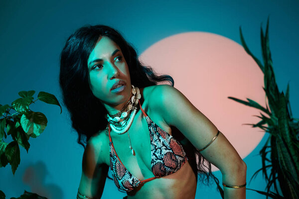 A stunning young woman poses gracefully against a vibrant backdrop, embodying summer fashion.