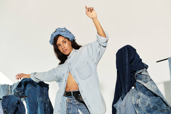 A stunning young woman poses elegantly, showcasing her denim outfit against a minimalist backdrop.