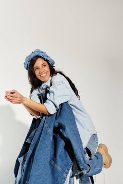 Kendine güveni tam bir genç kadın. Parlak bir alanda şık bir kot giysisinin modelliğini yapıyor..