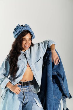 Modayı takip eden kot elbiseli kadın, bir stüdyo ortamında neşe ve yaz titreşimleri yayıyor..