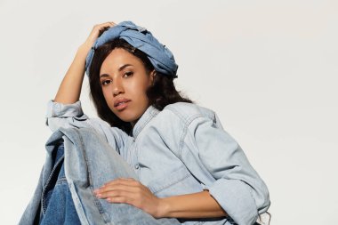 Güzel, genç bir kadın, kendine güvenen bir kot giysisi içinde, yaz modasını ve tarzını gözler önüne seriyor..