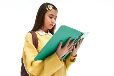 Modayı takip eden okul üniformalı genç Asyalı bir kız, etrafı hafif ışıkla çevriliyken bir defter okuyor..