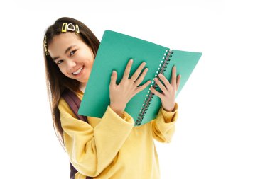 Neşeli bir Asyalı kız öğrenci şık üniformasını ve parlak gülümsemesini stüdyoda sergiliyor..