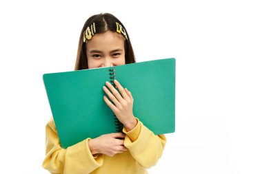 Modayı takip eden üniformalı neşeli Asyalı bir kız gülümseyerek yeşil bir not defteri tutuyor..