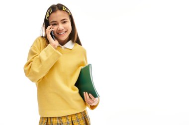 Şık üniformalı canlı bir Asyalı kız telefonda gülümserken konuşuyor..