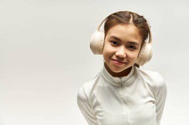 Sağlıklı ve kulaklıklı genç bir kız canlı bir stüdyoda güven içinde müzik dinlerken poz veriyor..