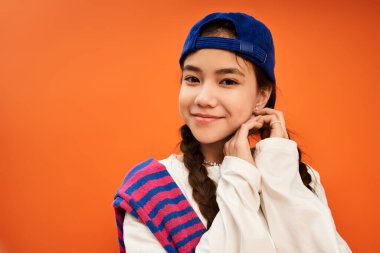 Modayı takip eden Asyalı bir genç kız canlı bir stüdyo ortamında neşeli bir gülümsemeyle poz veriyor..