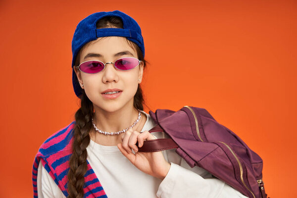 Азиатская девочка-подросток уверенно позирует в шикарном наряде, стоя в студии.