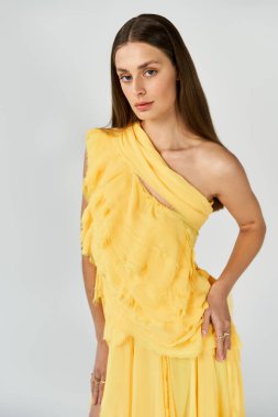 Güzel, genç bir kadın, kendinden emin bir şekilde sarı elbiseyle poz veriyor..