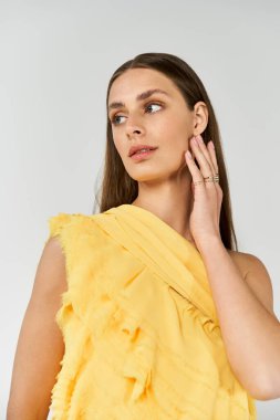 Güzel genç bir kadın zarif bir şekilde poz veriyor. Parlak sarı bir kıyafet içinde, yaz tarzını sergiliyor..