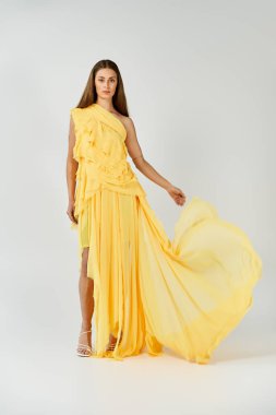 Göz kamaştırıcı bir kadın canlı, sarı bir elbiseyle şık bir şekilde poz verir..