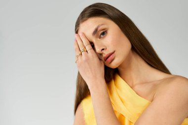 Göz kamaştırıcı genç bir kadın, parlak bir yaz kıyafetiyle neşe içinde poz verirken güzelliğini sergiliyor..