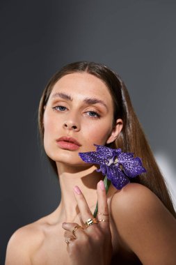 Genç bir kadın çarpıcı bir çiçekle zarifçe poz verir..