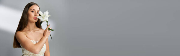 A young woman holds a white flower, showcasing grace and elegance during a summer moment.