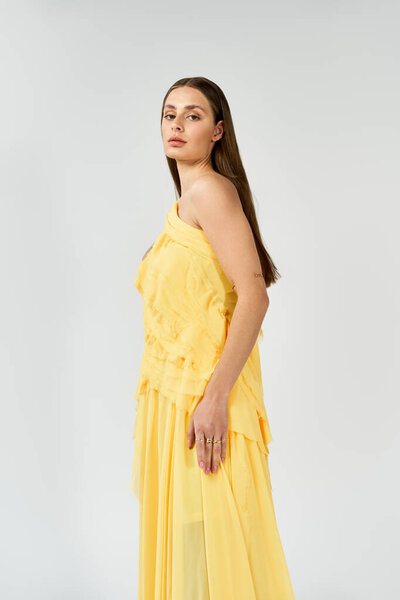 Молодая женщина сияет в ярком желтом платье, излучая элегантность и уверенность.