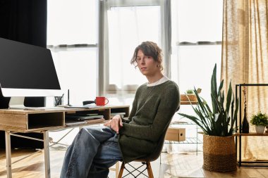 Genç adam çalışma alanında düşünceli bir şekilde oturur. Huzurlu bir yuva ortamında ders çalışır..