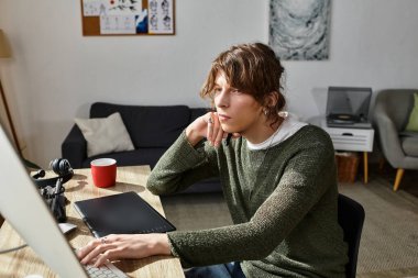 Genç bir adam evdeyken bilgisayarla derslerine konsantre oluyor..