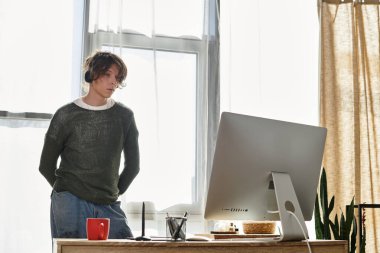 Kendini işine adamış genç bir adam doğal ışıkla çevrili rahat evinde özenle çalışıyor..