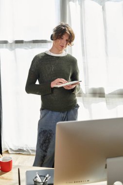 Genç bir öğrenci evde duruyor, derslerine dalmış, not almaya hazır..