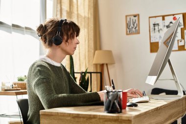 Konsantre olmuş, rahat kazaklı genç adam bir masada çalışıyor, çalışıyor ve notlar alıyor..