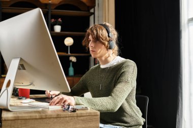 Bir adam evde derslerine konsantre oluyor, rahat ve düzenli bir çalışma alanı ile çevrili..