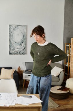 Odaklanmış genç adam evde rahat ve davetkar bir atmosferde çalışma materyallerini inceliyor..