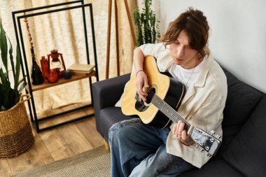 Genç bir öğrenci sakin ve davetkar bir ortamda gitarını tıngırdatmaktan hoşlanır..