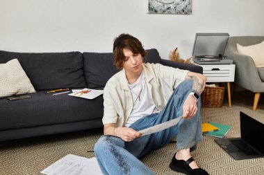 Odaklanmış genç bir öğrenci rahat bir ev ortamında otururken notlarını gözden geçirir..