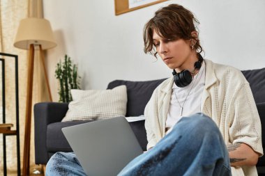 Odaklanmış genç bir adam, sessiz bir öğleden sonra evinde laptopuyla dikkatlice çalışır..