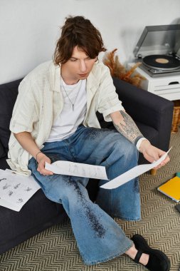 Odaklanmış öğrenci, rahat bir atmosferde rahat bir ev ortamı ile çevrili kağıtları inceliyor..