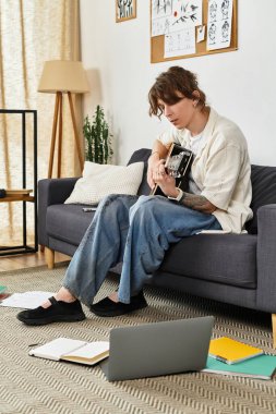 Genç bir öğrenci evde dinleniyor, bir gitar eşliğinde çalışmalar yapıyor..