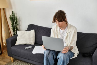 Genç öğrenci, rahat bir ortamda notlarla çevrili bir dizüstü bilgisayarda dikkatle çalışıyor..