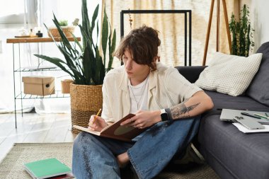 Çalışmalarla çevrili odaklanmış öğrenci evde yaratıcılığını geliştirirken fikirleri not alıyor.