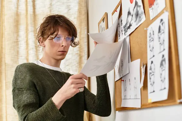 Odaklanmış genç bir adam, sanatsal çizimlerini evde, ilham ve yaratıcılıkla çevrili olarak değerlendiriyor..